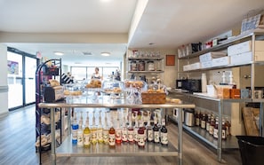 Eine Bäckerei mit Regalen voller Gläser mit Honig und anderen Gewürzen, einer Vitrine mit Gebäck und einer Theke mit Brot und Backwaren.