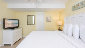 Hotelkamer met een bed, een televisie op een dressoir, een plafondventilator, een deur en een decoratie aan de muur.