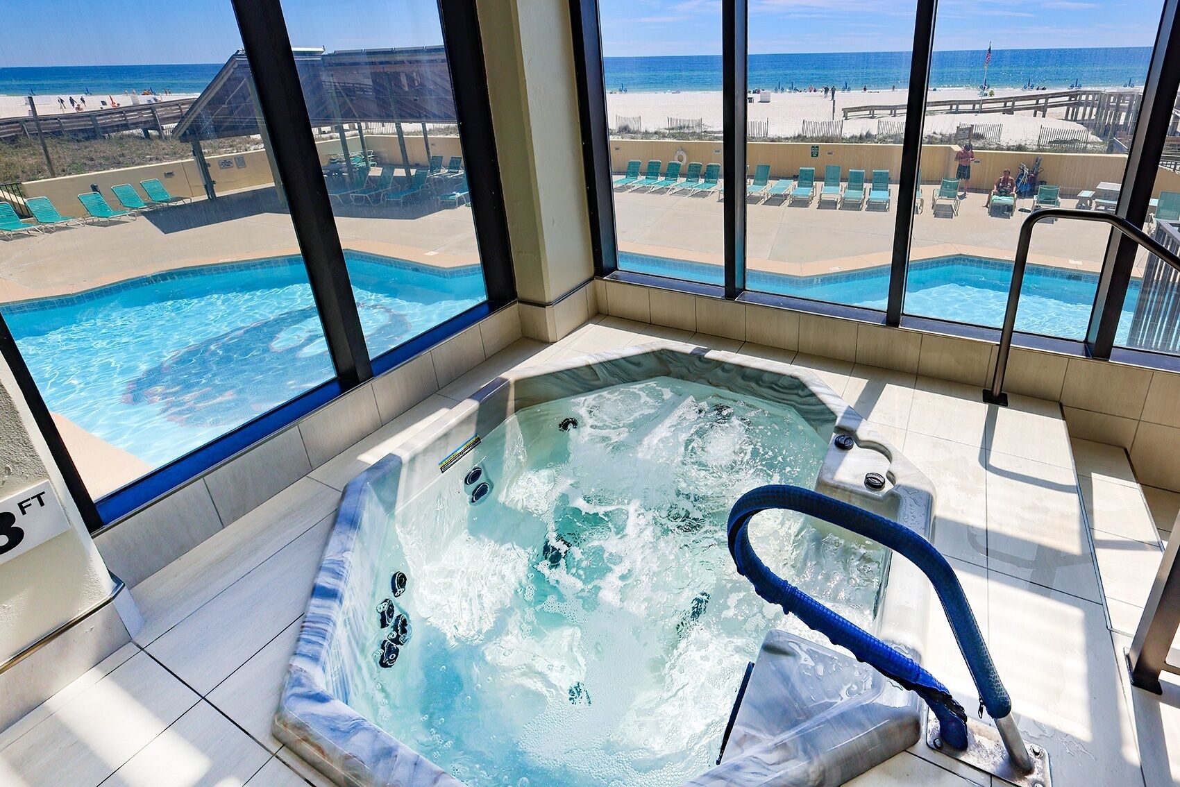 A hot tub with a view of a beach and pool area.