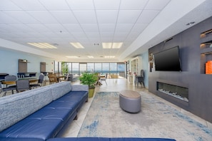 A modern office space with a large sofa, a flat-screen TV, and a fireplace. - Phoenix V 1511 1 Bedroom Condo (Orange Beach)