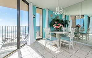 A balcony with a view of the sea, a dining area with a round table and chairs, and a large mirror reflecting the room. - Phoenix V 602 1 Bedroom Condo (Orange Beach)