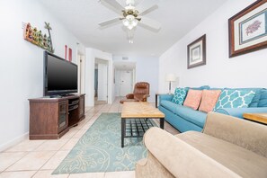 Ein Wohnzimmer mit Fernseher, Sofa, Couchtisch und Deckenventilator.
