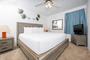 A hotel room with a bed, nightstands, a television, a ceiling fan, and a mirror. - Phoenix V 711 1 Bedroom Condo (Orange Beach)