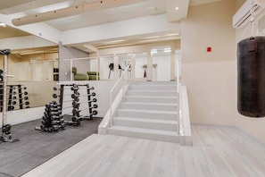 Ein Fitnessstudio mit Treppe, Krafttrainingsgeräten und einem Schlagbeutel.