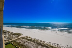 Ein Strand mit blauem Himmel, sandigem Ufer und einigen Personen.
