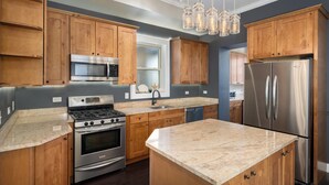 A modern kitchen with wooden cabinets, stainless steel appliances, and a granite countertop. - Beautiful, Spacious 3BR Ukrainian Village Home w/ Deck, Garage & Room for Groups (Chicago)