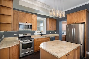 A modern kitchen with wooden cabinets, stainless steel appliances, and a granite countertop. - Beautiful, Spacious 3BR Ukrainian Village Home w/ Deck, Garage & Room for Groups (Chicago)
