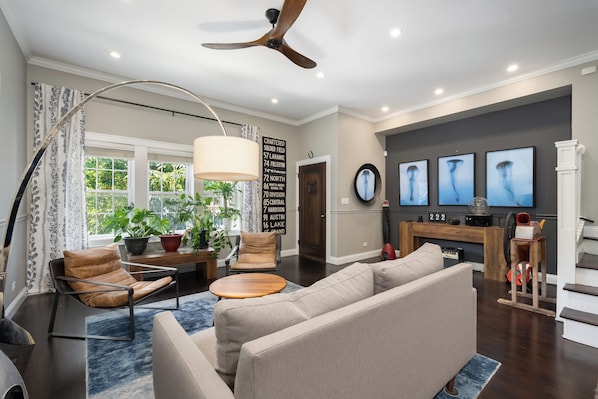 A modern living room with a ceiling fan, a fireplace, and a television.