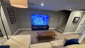 A living room with a large flat-screen TV, a wooden coffee table, and beige sofas. - Beautiful, Spacious 3BR Ukrainian Village Home w/ Deck, Garage & Room for Groups (Chicago)