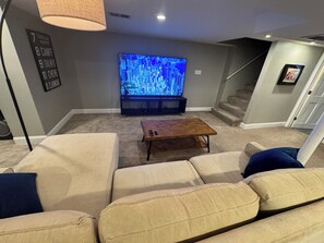 A living room with a large flat-screen TV, a wooden coffee table, and beige sofas. - Beautiful, Spacious 3BR Ukrainian Village Home w/ Deck, Garage & Room for Groups (Chicago)