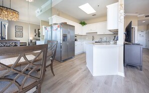 A modern kitchen with white cabinetry, stainless steel appliances, and a central island. - Phoenix V 111 1 Bedroom Condo (Orange Beach)