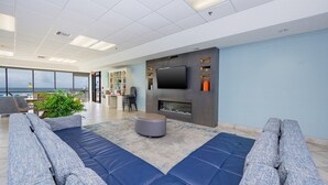A modern living room with a large sofa, ottoman, and a flat-screen TV mounted on a wall. - Phoenix V 111 1 Bedroom Condo (Orange Beach)