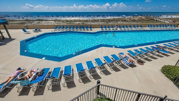 A swimming pool with lounge chairs and a view of the beach. - Phoenix V 111 1 Bedroom Condo (Orange Beach)