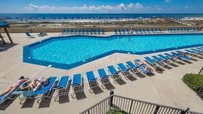 Ein Swimmingpool mit Liegestühlen und Blick auf den Strand.