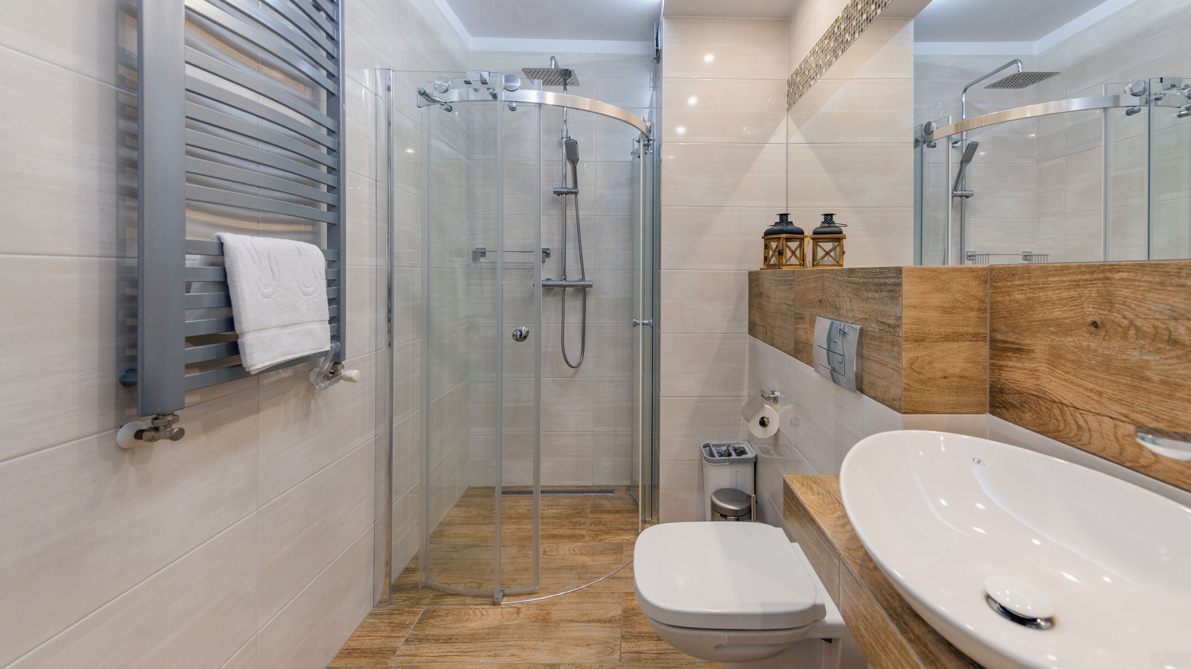 Un baño moderno con ducha de vidrio, tocador de madera y un inodoro blanco.