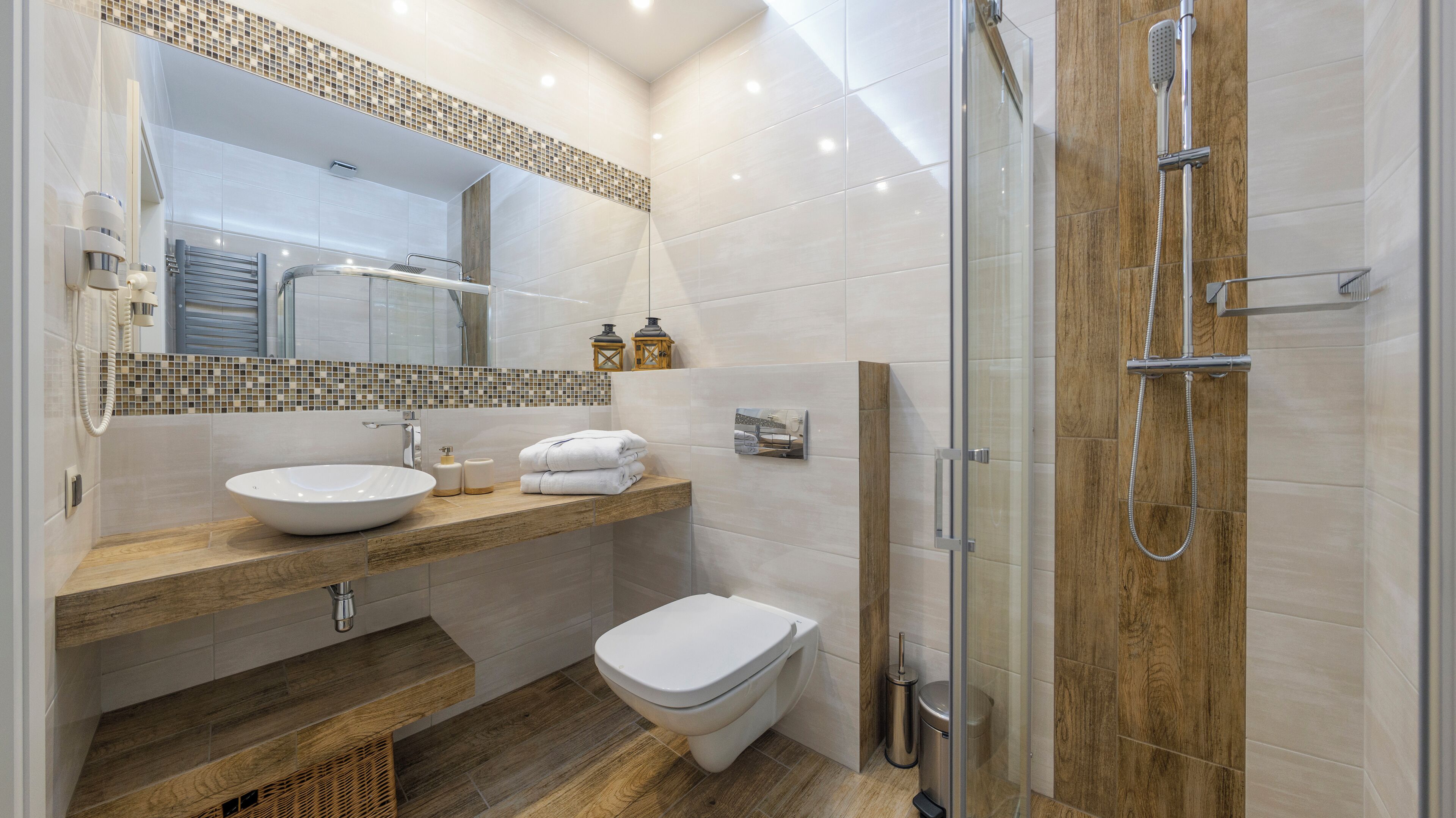 Une salle de bain moderne avec une douche à parois de verre, un meuble-lavabo en bois et des toilettes blanches.