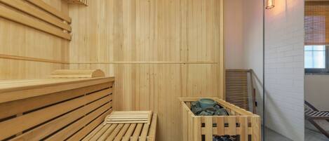 A wooden sauna with benches and a stone basin.