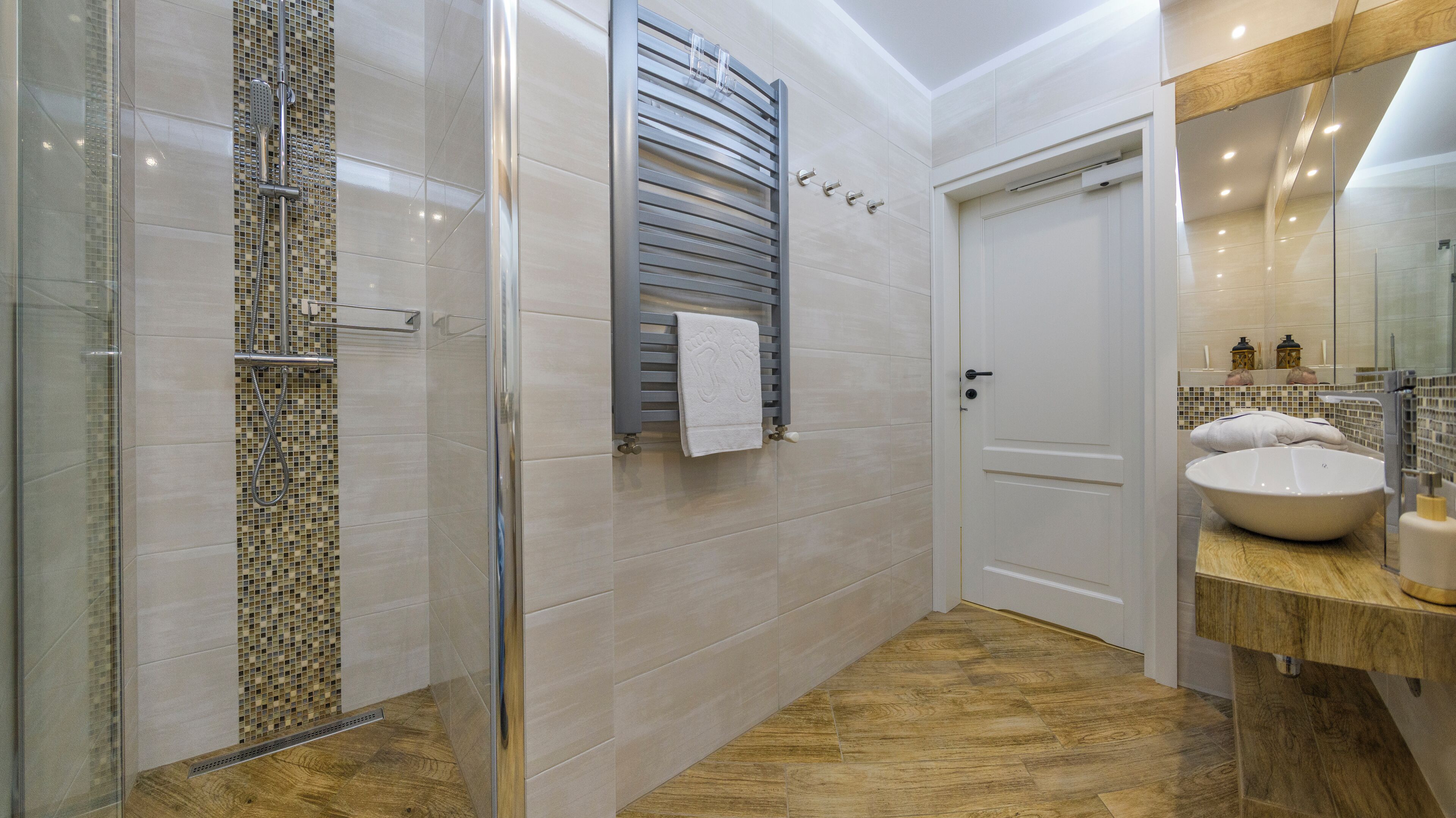 A modern bathroom with a glass shower enclosure, a wooden vanity, and a large mirror.