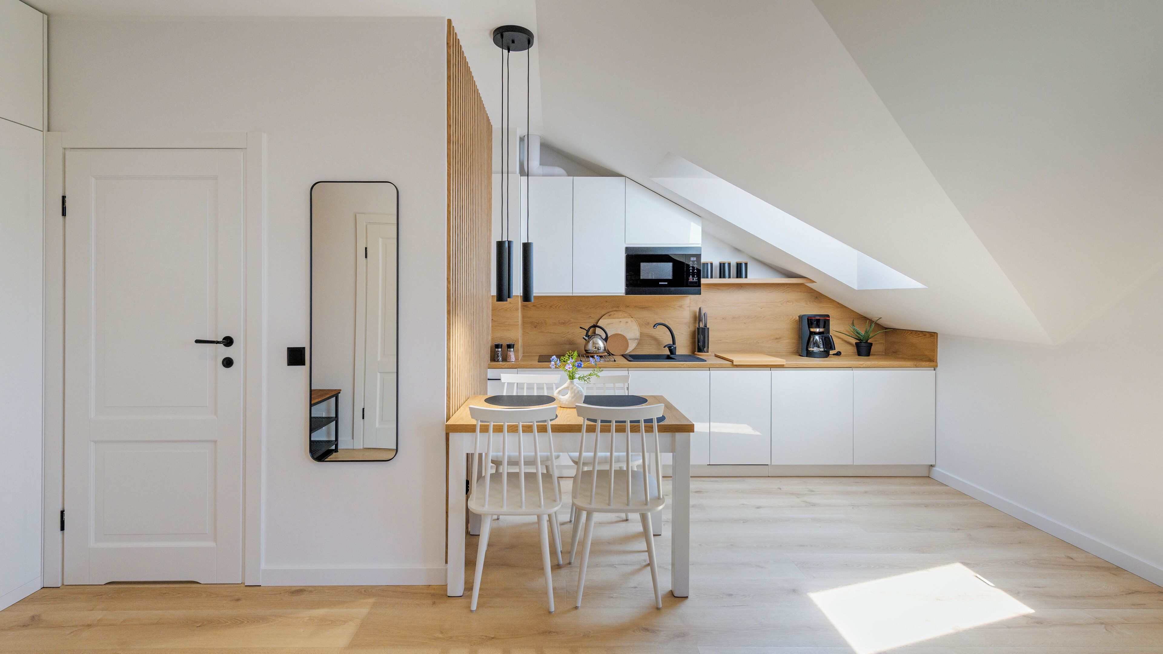 A modern kitchen with a wooden countertop, white cabinets, and a black microwave.