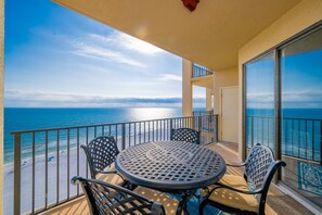 Ein Balkon mit Tisch und Stühlen mit Blick auf einen Strand und den Ozean.