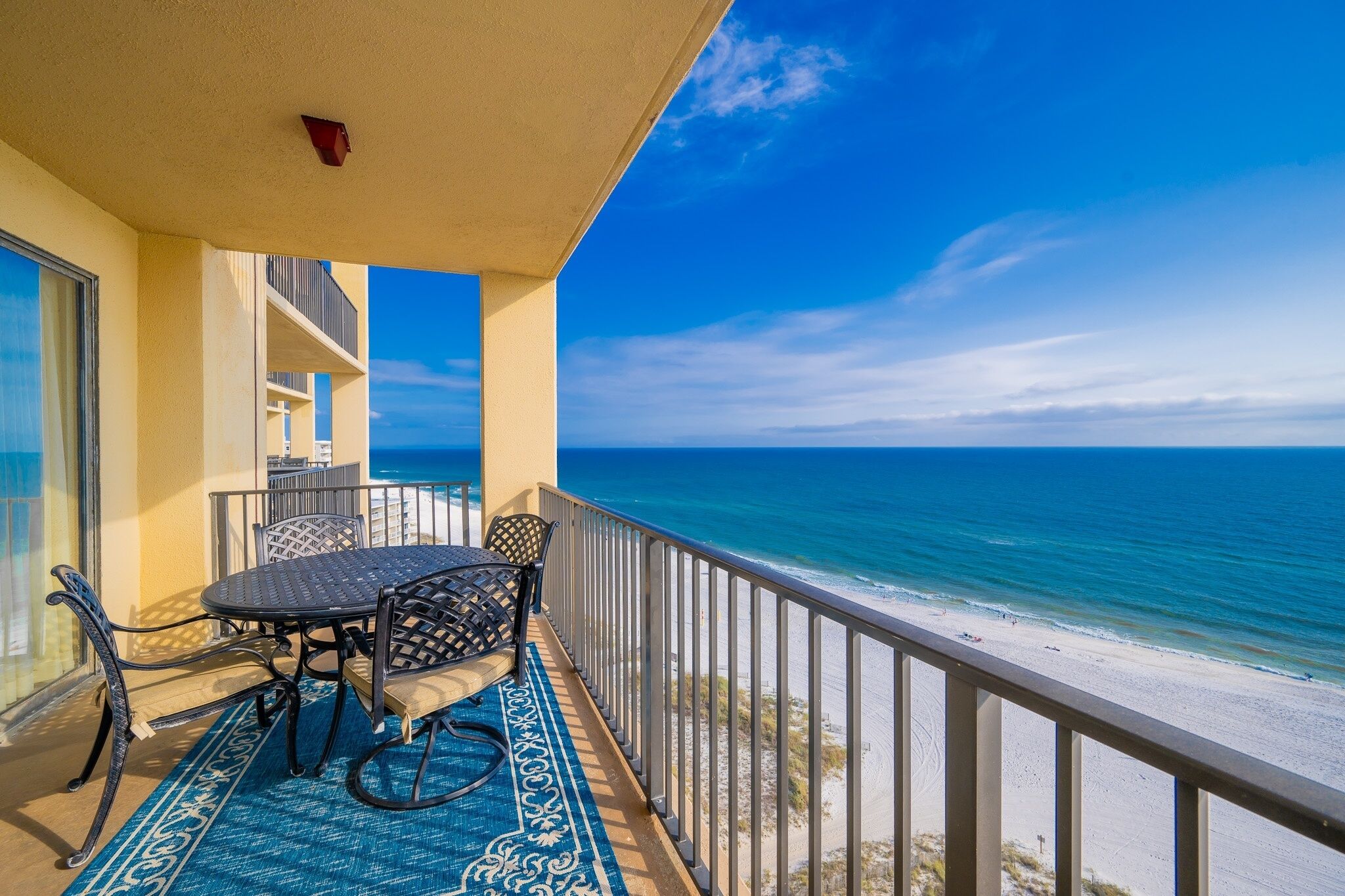 Ein Balkon mit Tisch und Stühlen, mit Blick auf Strand und Meer.