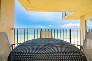 Ein Balkon mit Blick auf den Strand, einem runden Tisch und zwei Stühlen.