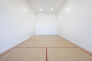 A squash court with white walls and a light-colored floor, equipped with two ceiling lights. - Phoenix I 1146 1 Bedroom Condo (Orange Beach)