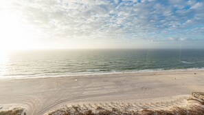 Ein Strand mit blauem Himmel, ruhiger See und sandigem Ufer.