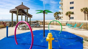 Ein Wasserspielbereich mit Hydrant, Kiosk und Liegestühlen am Pool.