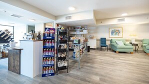 Ein modernes Interieur mit einer Rezeption, einem Getränkeautomaten und einer Sitzecke mit einem grünen Sofa und Sesseln.
