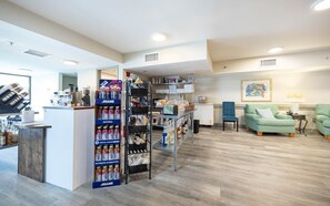 Ein modernes Interieur mit einer Rezeption, einem Getränkeautomaten und einer Sitzecke mit einem grünen Sofa und Sesseln.