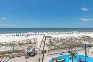 Ein Strandresort mit Promenadenweg, Strandstühlen, Liegestühlen und einem Swimmingpool.