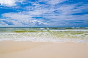Ein Strand mit Wellen und blauem Himmel.