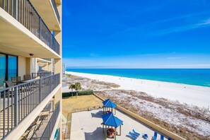 Ein Hotelbalkon direkt am Strand mit Sitzgelegenheiten im Freien und Blick auf den Strand.