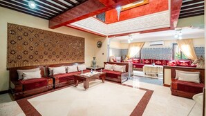 A spacious living area with a high ceiling, a decorative wall, and a seating arrangement including sofas and a coffee table.