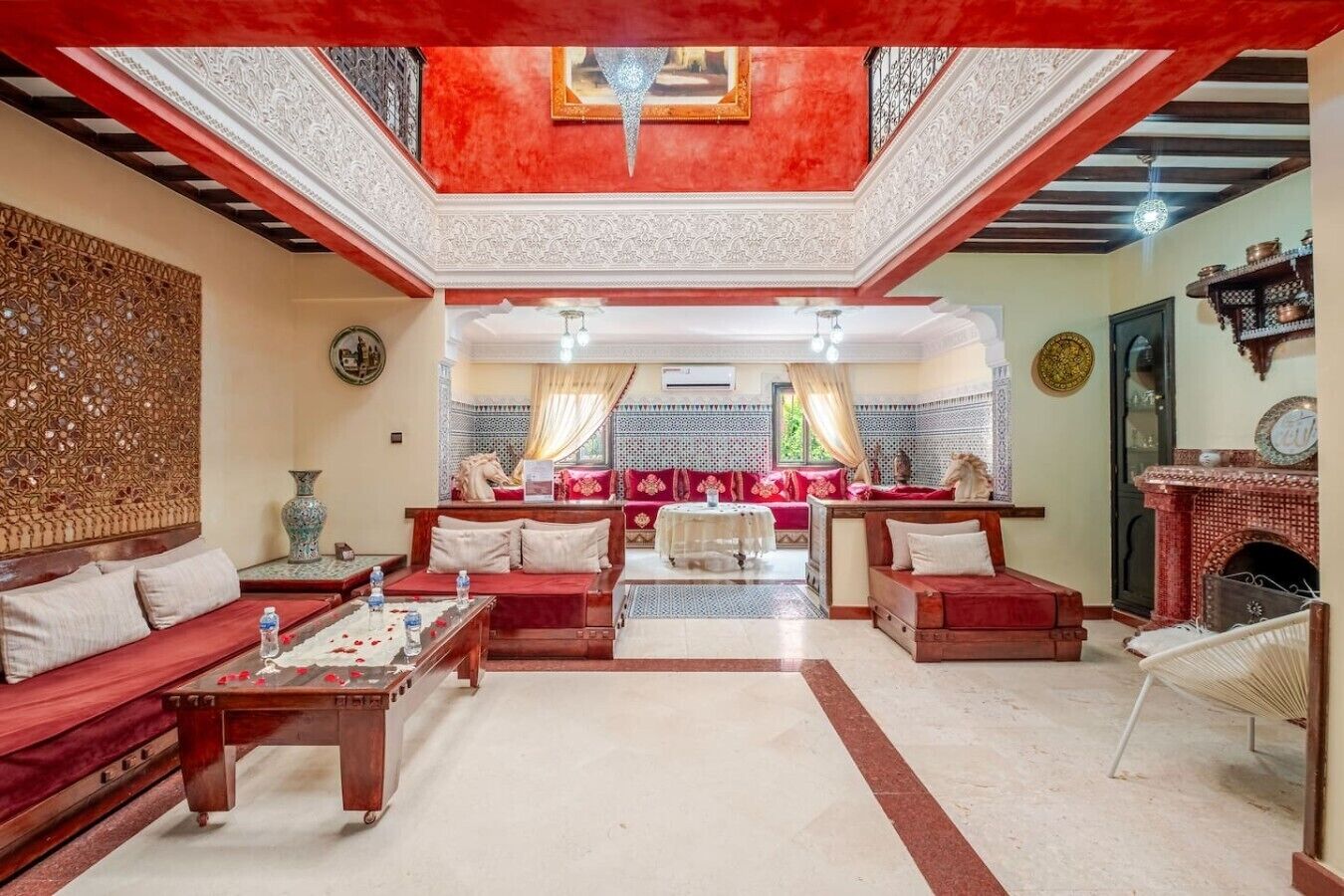 A spacious living room with a high ceiling, a fireplace, and a sofa set.
