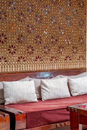 A sofa with cushions and a wooden headboard with intricate patterns. - 3ch, piscine proche Médina, résidence sécurisée (Marrakesh)