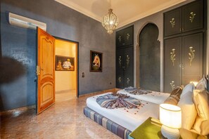 A bedroom with a bed, a nightstand, a lamp, a chandelier, and a wardrobe. - Villa Piscine / Hammam / 10 min de Centre (Marrakesh)