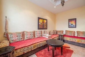 A living room with a sofa set, a small table, and two wall-mounted paintings. - Villa Piscine / Hammam / 10 min de Centre (Marrakesh)