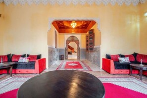 A room with two sofas, a round table, and a decorative archway leading to a hallway. - Villa Piscine / Hammam / 10 min de Centre (Marrakesh)