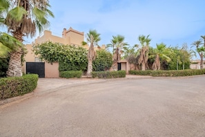A residential area with a paved road, palm trees, and a building with a beige facade. - Villa Piscine / Hammam / 10 min de Centre (Marrakesh)