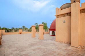 A rooftop terrace with a red dome structure, beige pillars, and a clear sky. - Villa Piscine / Hammam / 10 min de Centre (Marrakesh)