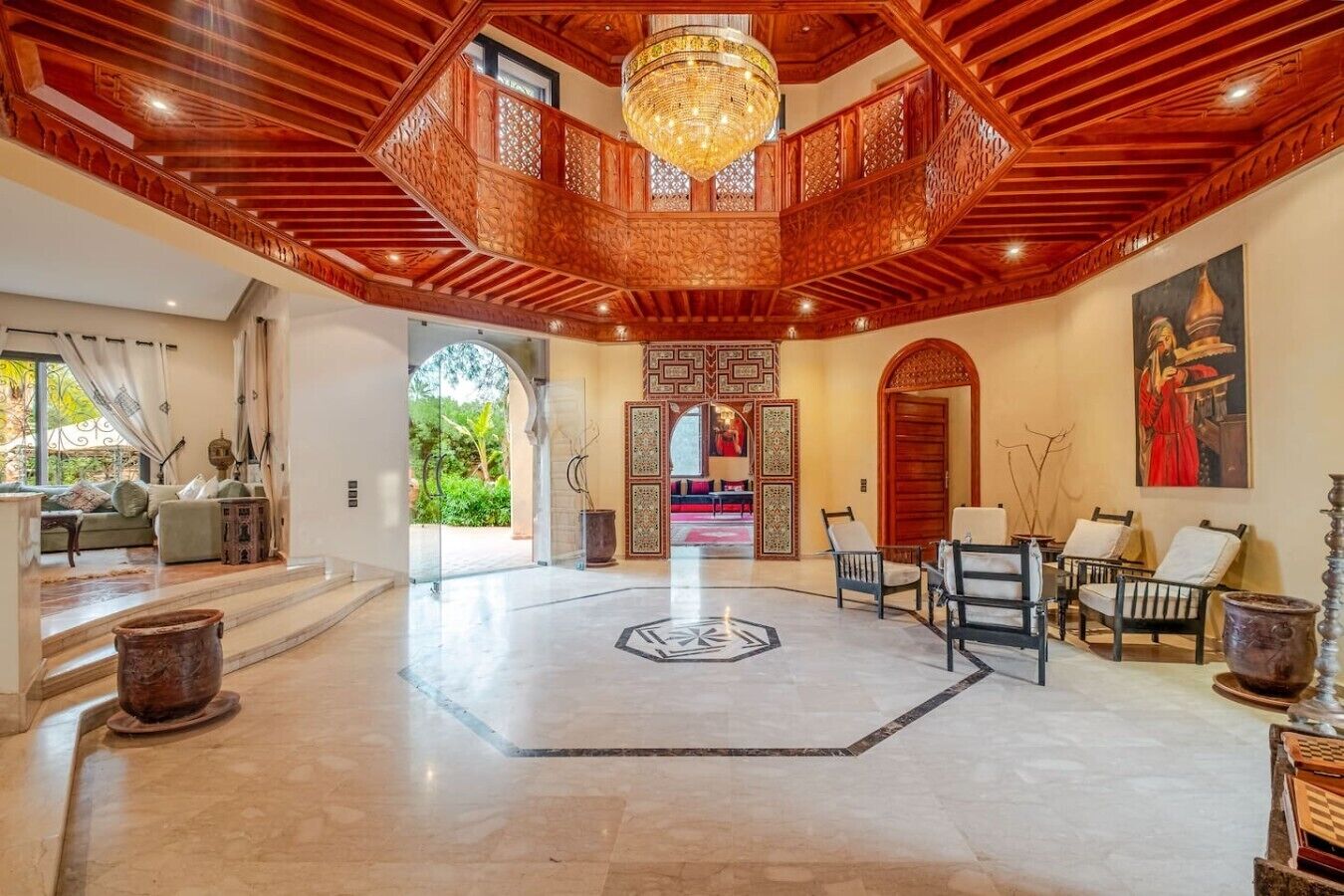 A spacious lobby with a high ceiling, a central chandelier, and a seating area with chairs and a sofa.