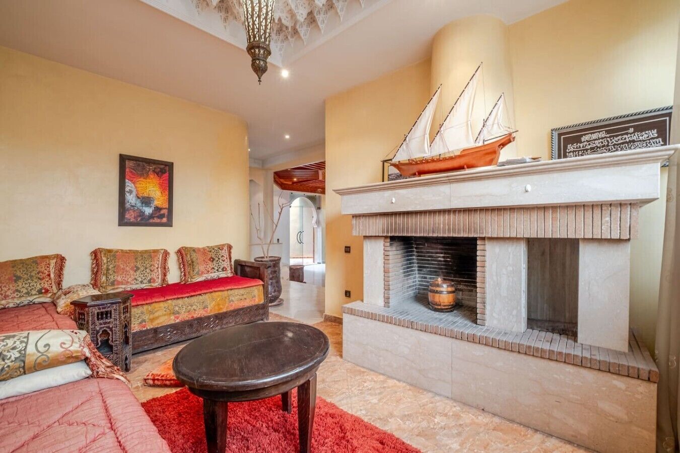 A living room with a fireplace, a sofa, a coffee table, and a ship model on the mantel.