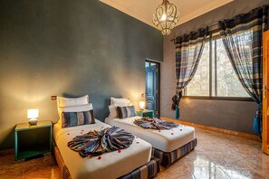 A hotel room with two beds, a chandelier, a window with curtains, and a door. - Villa Piscine / Hammam / 10 min de Centre (Marrakesh)