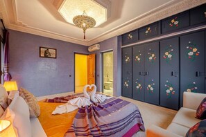 Een hotelkamer met een bed, een bank, een kroonluchter en een garderobe met bloemenmotieven.