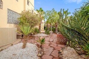 A courtyard with a stone pathway, palm trees, and cacti. - Villa Piscine / Hammam / 10 min de Centre (Marrakesh)