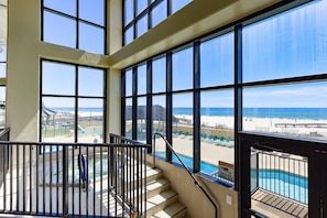 A hotel room with large windows overlooking a beach and pool area. - Phoenix I 1114 1 Bedroom Condo (Orange Beach)