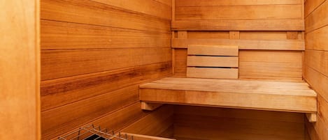 Uma sauna de madeira com bancos e uma estante de metal.