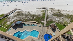 A rooftop pool with a view of the beach, lounge chairs, and a flag. - Phoenix I 1114 1 Bedroom Condo (Orange Beach)